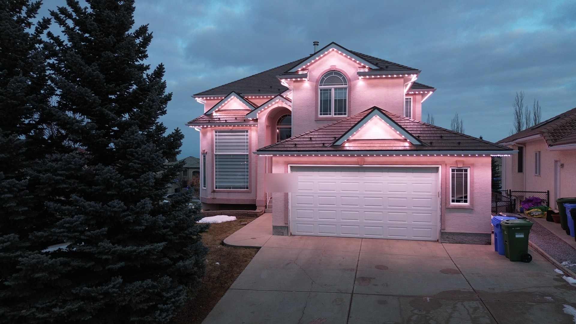 The same home at dusk in deep magenta and pink, the colour washing across the stucco and driveway.