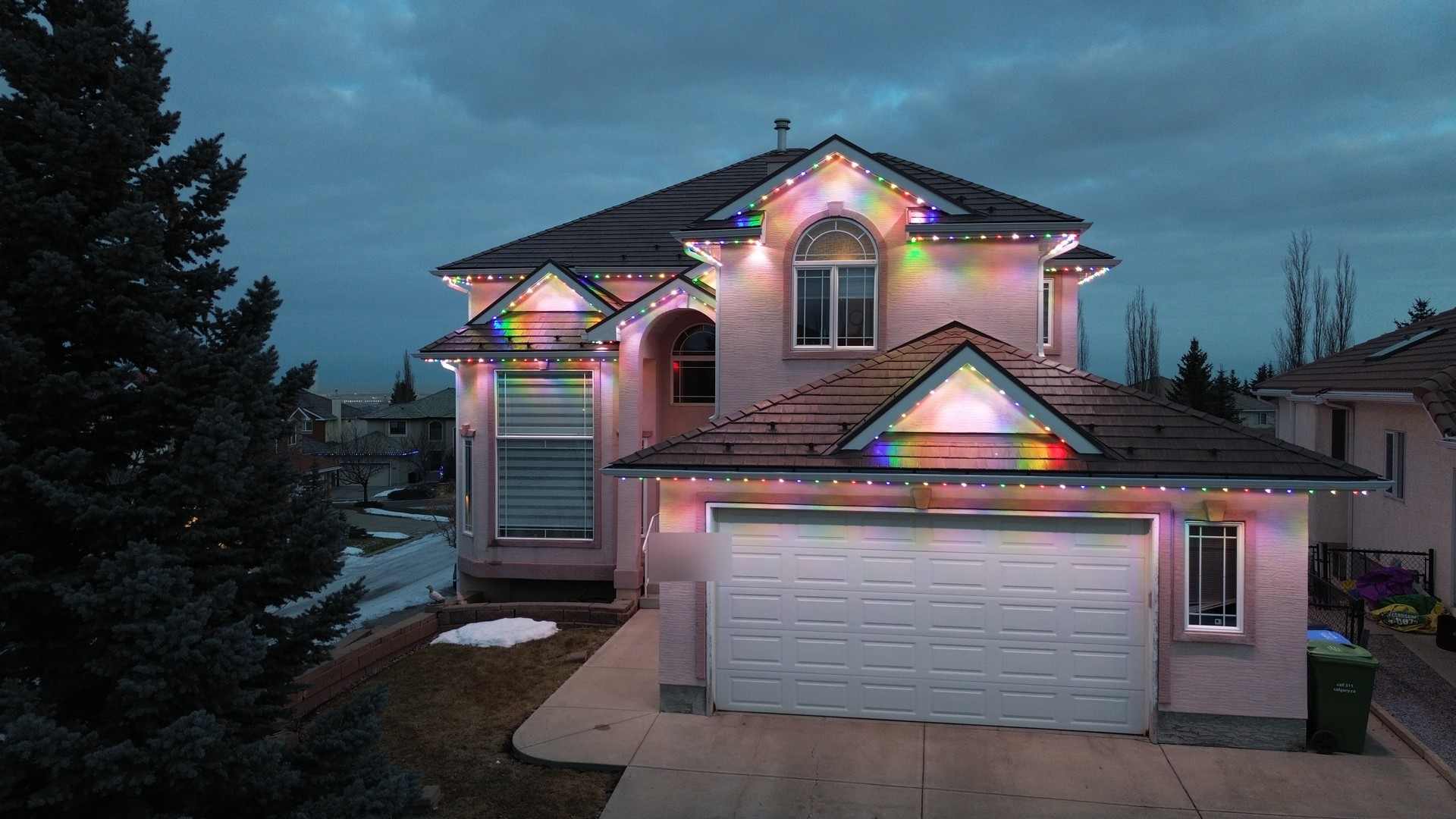 The same home at dusk running a full multicolour scene, each roofline light a different colour.